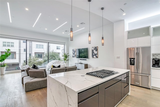 kitchen featuring light wood finished floors, visible vents, modern cabinets, appliances with stainless steel finishes, and open floor plan