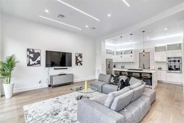 living room featuring baseboards, visible vents, light wood finished floors, and recessed lighting