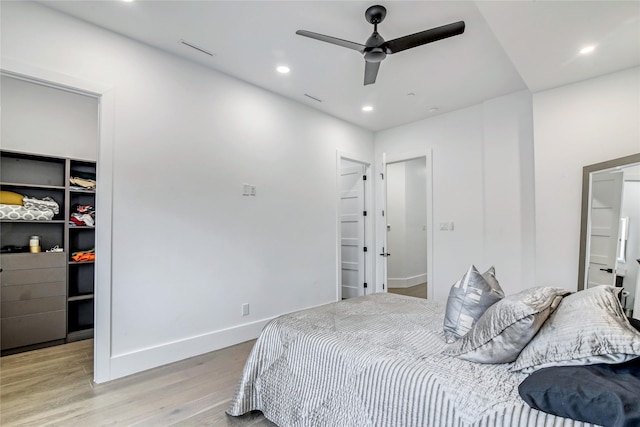 bedroom with recessed lighting, a spacious closet, light wood-type flooring, a closet, and baseboards