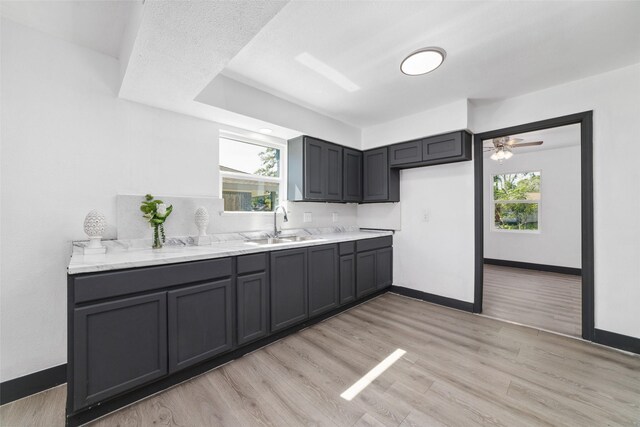 kitchen with light wood finished floors, a sink, baseboards, and a wealth of natural light