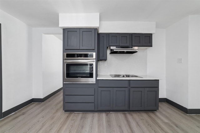kitchen with baseboards, light countertops, under cabinet range hood, stainless steel oven, and light wood-style flooring
