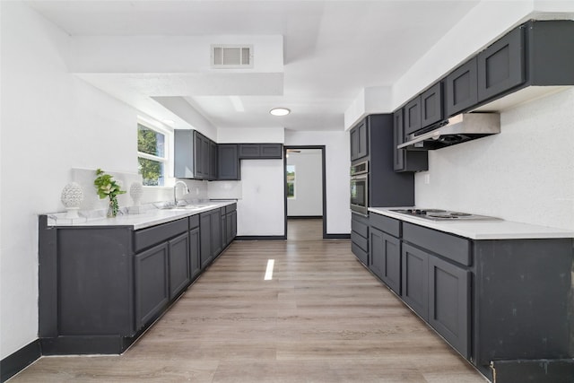 kitchen with under cabinet range hood, visible vents, oven, electric stovetop, and a sink