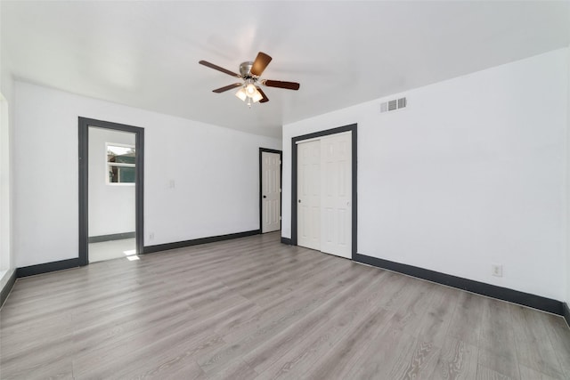 unfurnished room featuring light wood-style floors, baseboards, a ceiling fan, and visible vents
