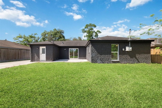 rear view of house featuring a patio, a yard, fence, and brick siding