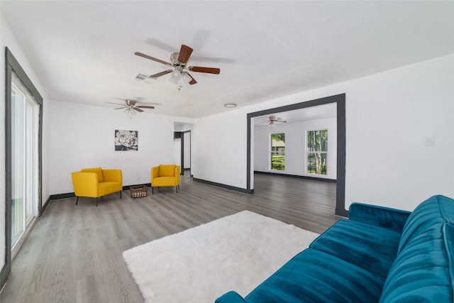 living room featuring wood finished floors, ceiling fan, baseboards, and visible vents