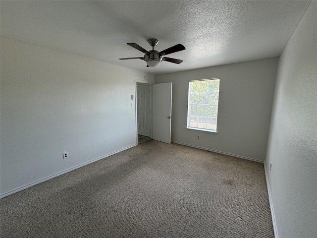 carpeted spare room featuring baseboards, a ceiling fan, and a textured ceiling