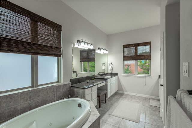 bathroom featuring tile patterned floors, vanity, baseboards, and a tub with jets