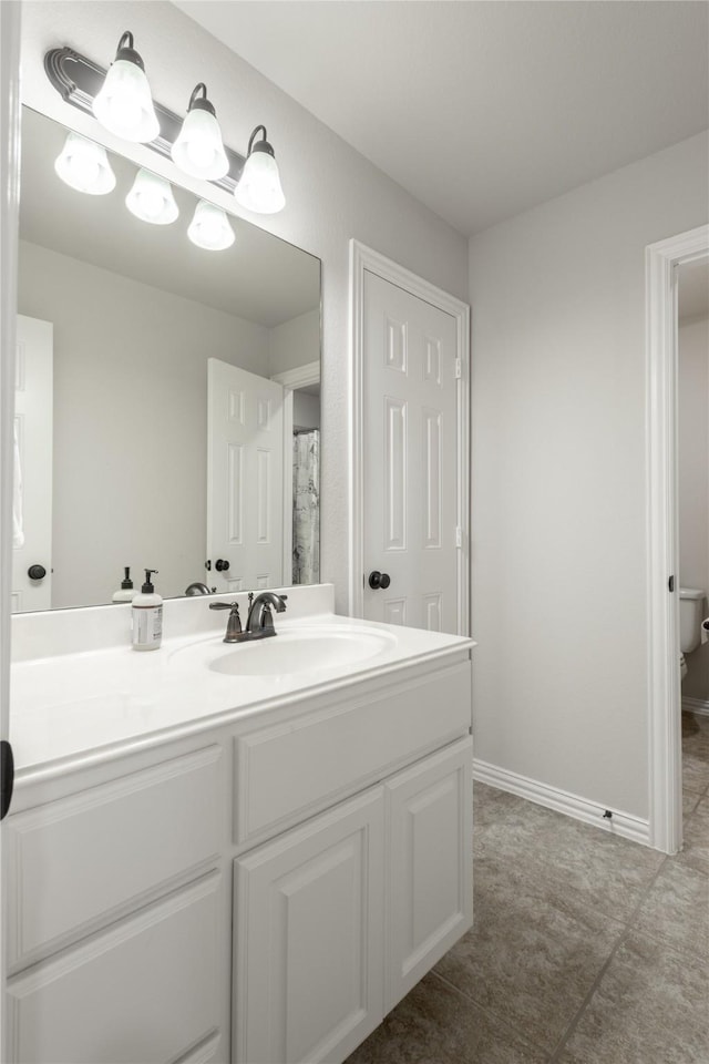 full bathroom with toilet, vanity, and baseboards
