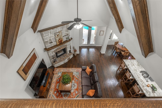 living area featuring a fireplace, hardwood / wood-style flooring, a ceiling fan, and lofted ceiling with beams