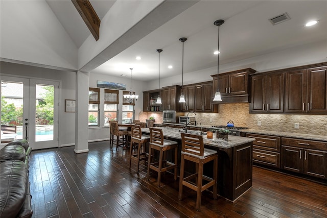 kitchen featuring tasteful backsplash, visible vents, a sink, dark brown cabinetry, and a breakfast bar area