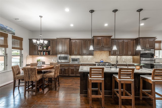 kitchen with open shelves, a center island with sink, dark brown cabinets, and appliances with stainless steel finishes