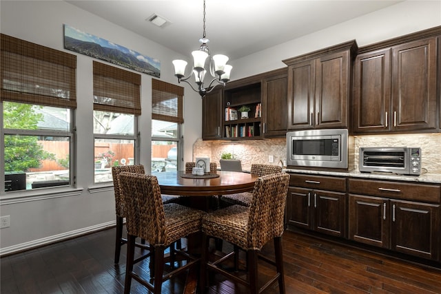 dining room featuring dark wood-style floors, an inviting chandelier, a toaster, and visible vents