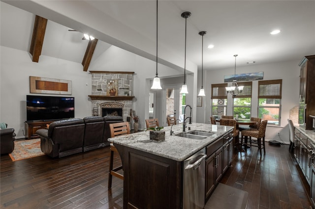 kitchen featuring a sink, a stone fireplace, dark brown cabinetry, dark wood-type flooring, and stainless steel dishwasher