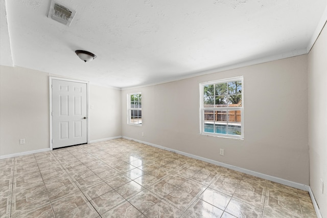 tiled empty room featuring baseboards, visible vents, and a healthy amount of sunlight