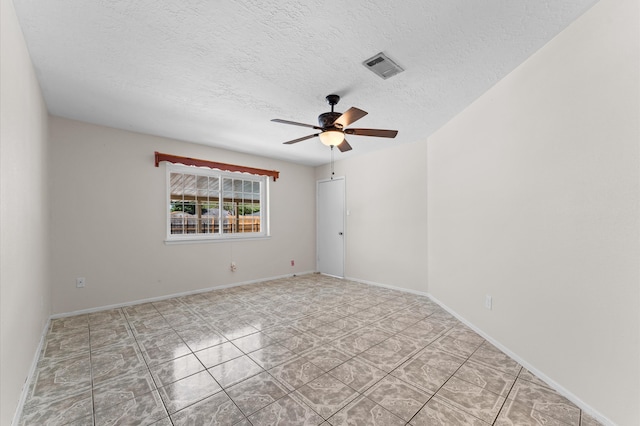 spare room with tile patterned flooring, ceiling fan, baseboards, visible vents, and a textured ceiling