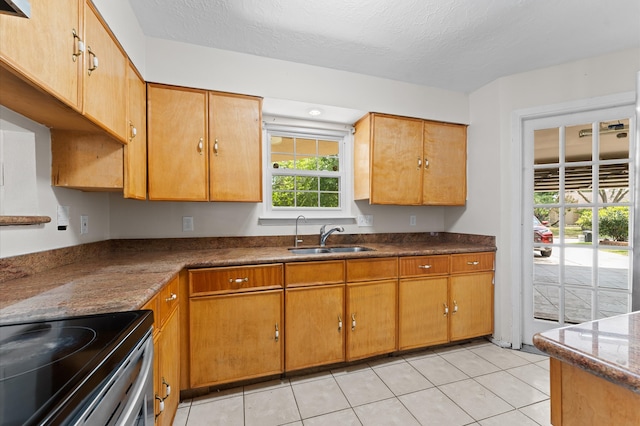 kitchen featuring light tile patterned floors, range with electric stovetop, dark countertops, a sink, and a textured ceiling