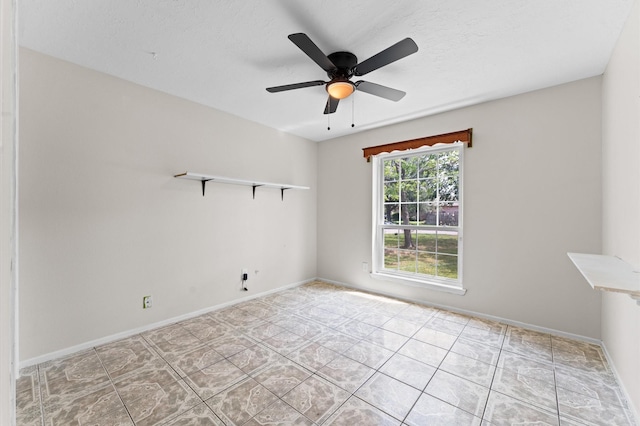 tiled empty room featuring ceiling fan and baseboards