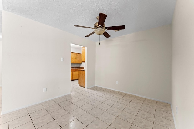 unfurnished room featuring light tile patterned flooring, ceiling fan, a textured ceiling, and baseboards
