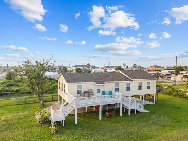 rear view of property featuring stairs, fence, a wooden deck, a lawn, and roof with shingles