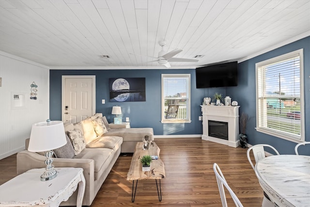 living area with wood finished floors, ceiling fan, a fireplace, baseboards, and visible vents