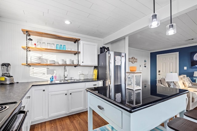 kitchen with dark countertops, a sink, freestanding refrigerator, electric range oven, and white cabinetry