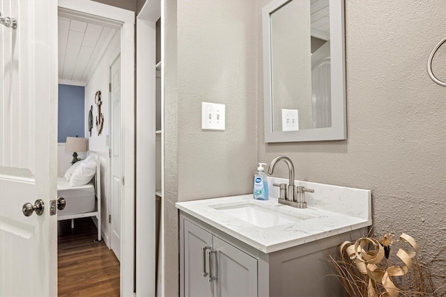 bathroom with a textured wall, vanity, and wood finished floors