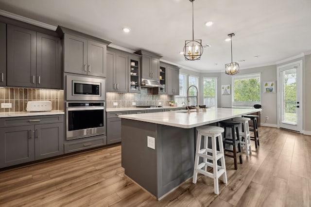 17583 Harpers Way, Conroe, TX 77385 - kitchen with crown molding, a sink, appliances with stainless steel finishes, gray cabinetry, and an inviting chandelier
