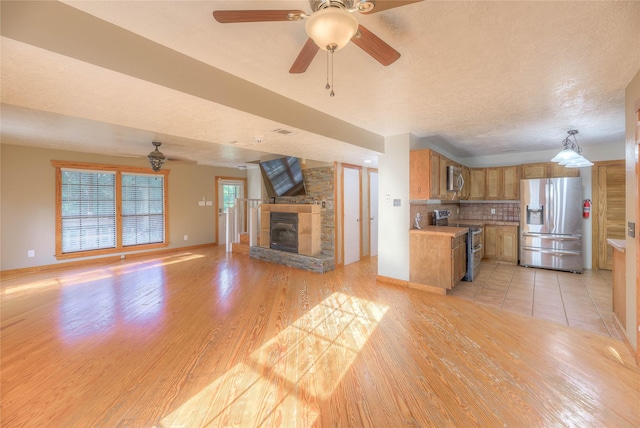 25 S Magnolia Ln, Shepherd, TX 77371 - unfurnished living room with a ceiling fan, a textured ceiling, light wood-style floors, a fireplace, and baseboards