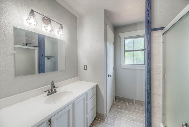25 S Magnolia Ln, Shepherd, TX 77371 - full bathroom featuring wood tiled floor, a textured wall, vanity, baseboards, and a stall shower