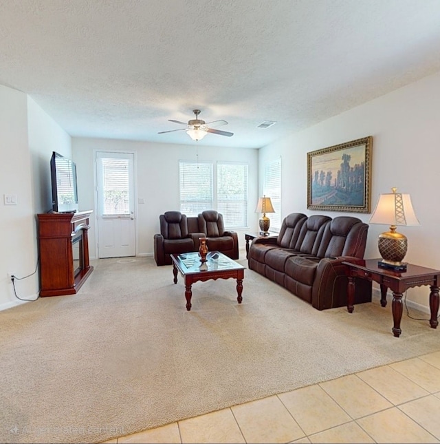 carpeted living area with baseboards, ceiling fan, tile patterned flooring, and a fireplace