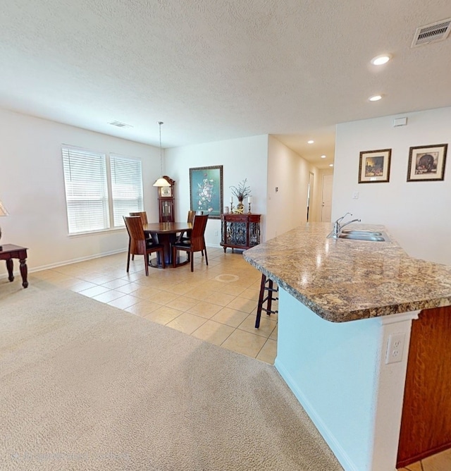 kitchen featuring visible vents, a sink, light carpet, recessed lighting, and light tile patterned flooring