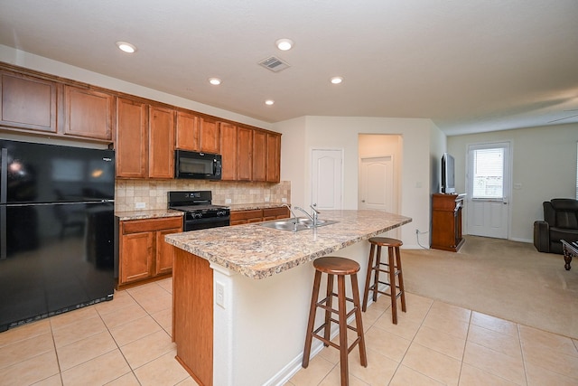 kitchen featuring light tile patterned floors, brown cabinetry, a sink, and black appliances
