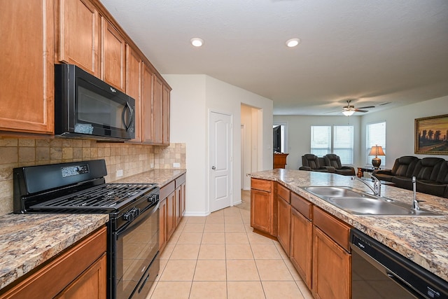 kitchen with open floor plan, a sink, backsplash, light tile patterned floors, and black appliances
