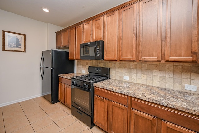 kitchen featuring baseboards, decorative backsplash, black appliances, and brown cabinets