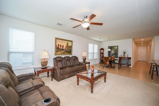 living area featuring a ceiling fan, visible vents, and light tile patterned flooring