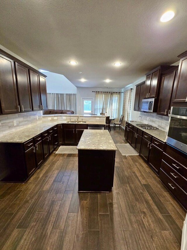 19003 Bene Vista Dr, Houston, TX 77084 - kitchen with appliances with stainless steel finishes, dark wood-style floors, decorative backsplash, light stone counters, and recessed lighting
