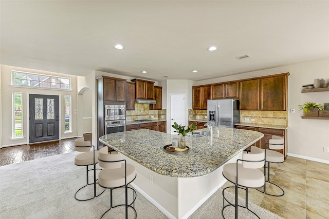 26818 Lindenwood Creek Ln, Katy, TX 77494 - kitchen with appliances with stainless steel finishes, a breakfast bar area, backsplash, a large island, and recessed lighting