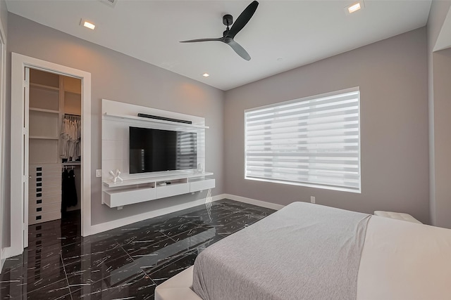bedroom with marble finish floor, a walk in closet, a closet, and baseboards