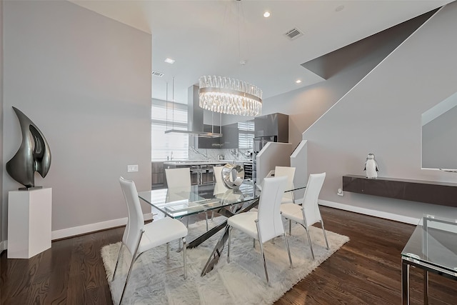 dining space with visible vents, wood finished floors, a chandelier, and baseboards