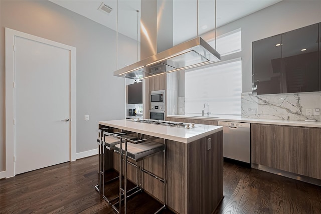 kitchen with appliances with stainless steel finishes, island exhaust hood, modern cabinets, and a sink