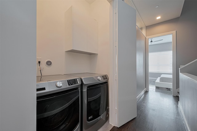 laundry area featuring washing machine and dryer, dark wood-style flooring, cabinet space, and baseboards