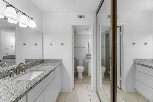 bathroom with a textured ceiling, tile patterned flooring, visible vents, toilet, and a sink