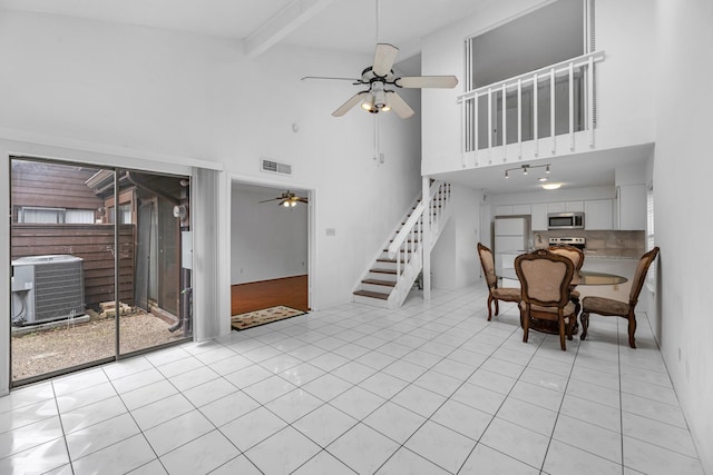 interior space with ceiling fan, a towering ceiling, visible vents, and stairs