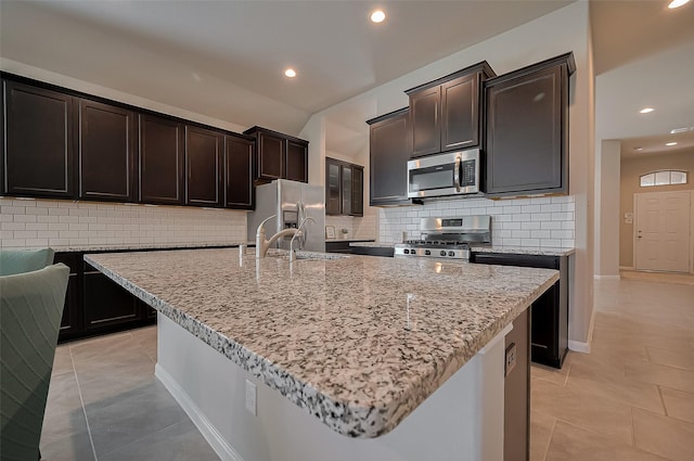 kitchen with light stone counters, decorative backsplash, stainless steel appliances, and recessed lighting