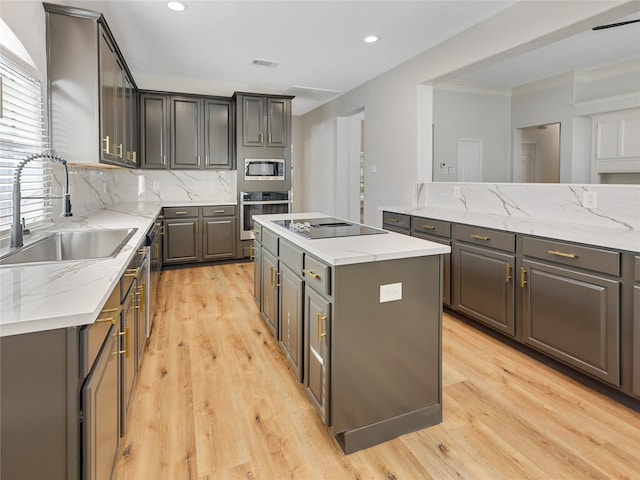 kitchen featuring gray cabinets, a center island, a sink, and stainless steel appliances