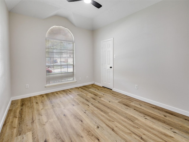spare room featuring wood finished floors, ceiling fan, baseboards, and vaulted ceiling