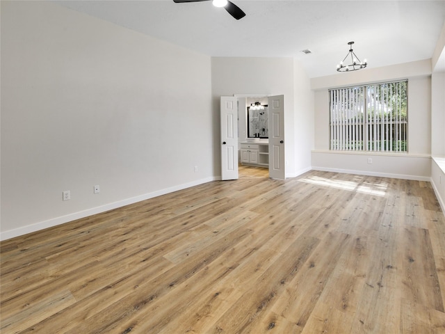 unfurnished living room featuring baseboards, vaulted ceiling, light wood-style floors, visible vents, and ceiling fan with notable chandelier