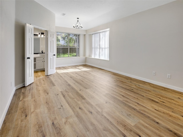 unfurnished dining area with light wood finished floors, an inviting chandelier, and baseboards