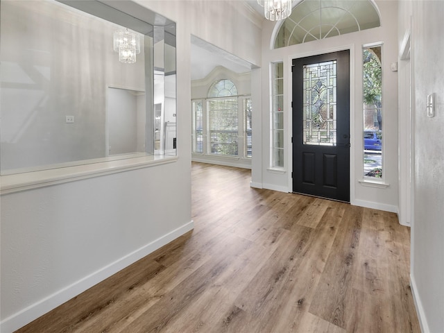 entrance foyer with baseboards, a notable chandelier, wood finished floors, and a healthy amount of sunlight