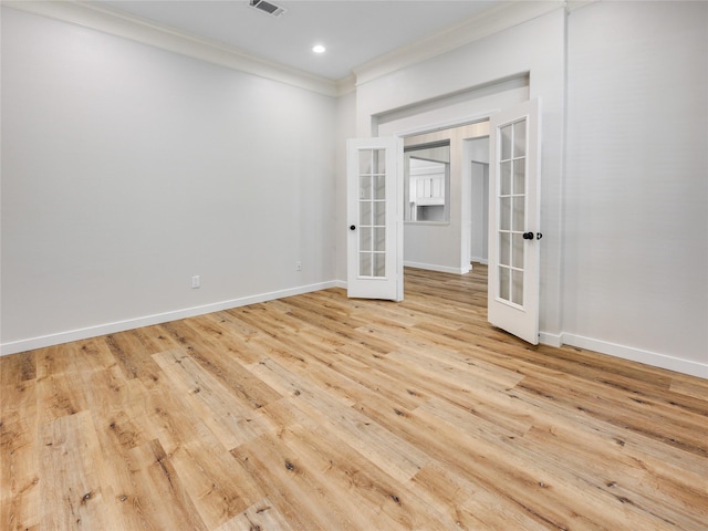 empty room featuring visible vents, baseboards, ornamental molding, light wood-style floors, and french doors